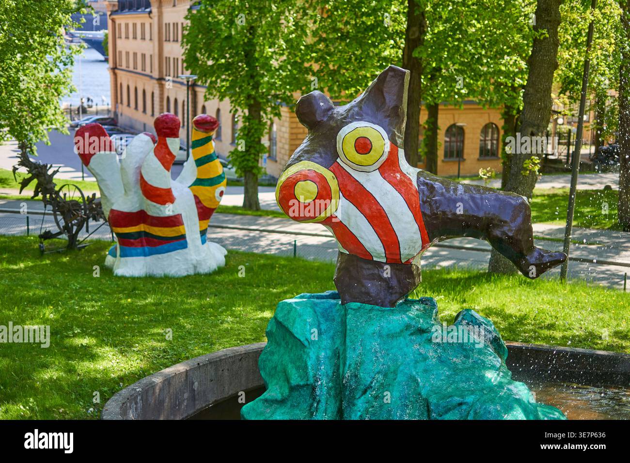 Sculture fantasiose e colorate in un contesto di parco all'aperto, con figure astratte dipinte con strisce audaci e occhi circolari. Una creatura viola Foto Stock