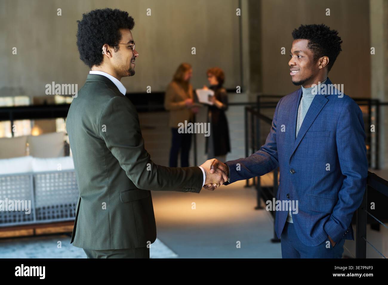 Uomini d'affari neri e di razza mista che stringono la mano dopo aver negoziato in carica Foto Stock