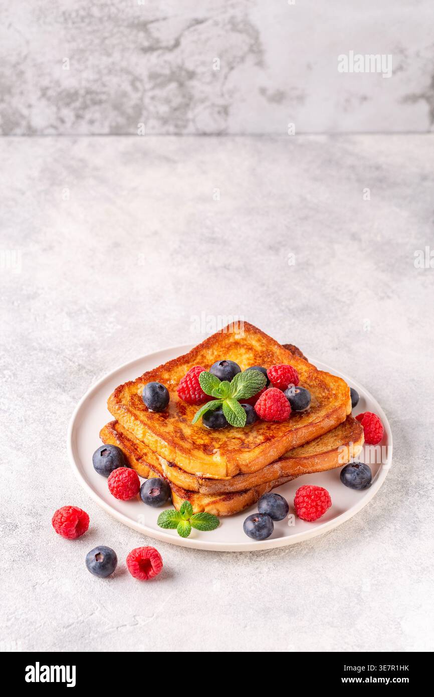 Toast alla francese con mirtilli, lamponi, sciroppo d'acero, colazione mattutina. Foto Stock