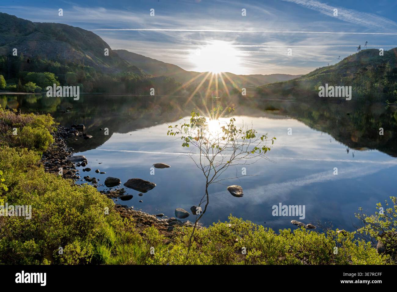 Il lago calmo di Loch Trool riflette l'alba e le montagne circostanti con la chiara luce del mattino. Foto Stock
