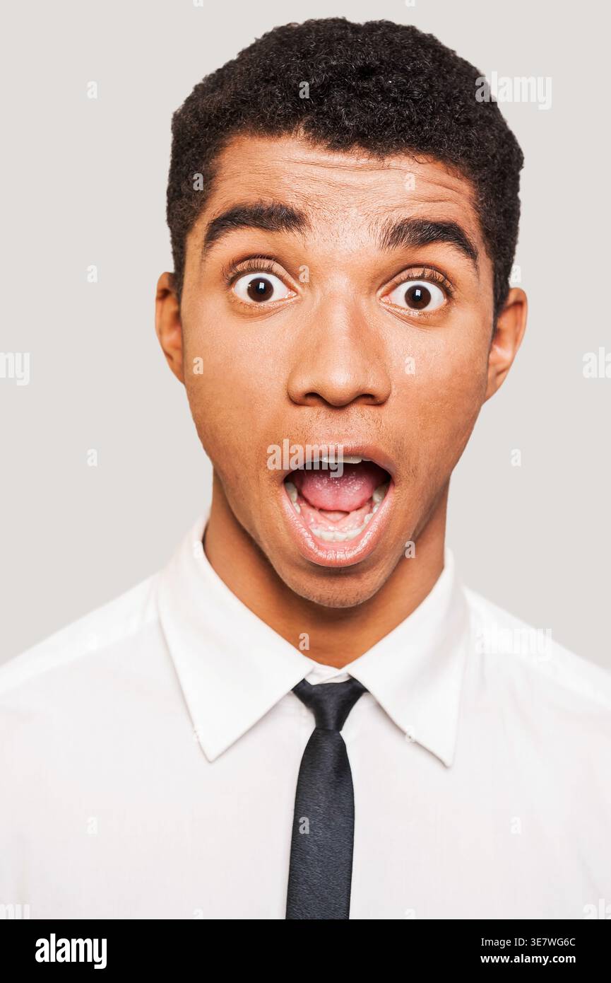 Shocked Black uomo d'affari con la bocca aperta sullo sfondo beige in studio Foto Stock