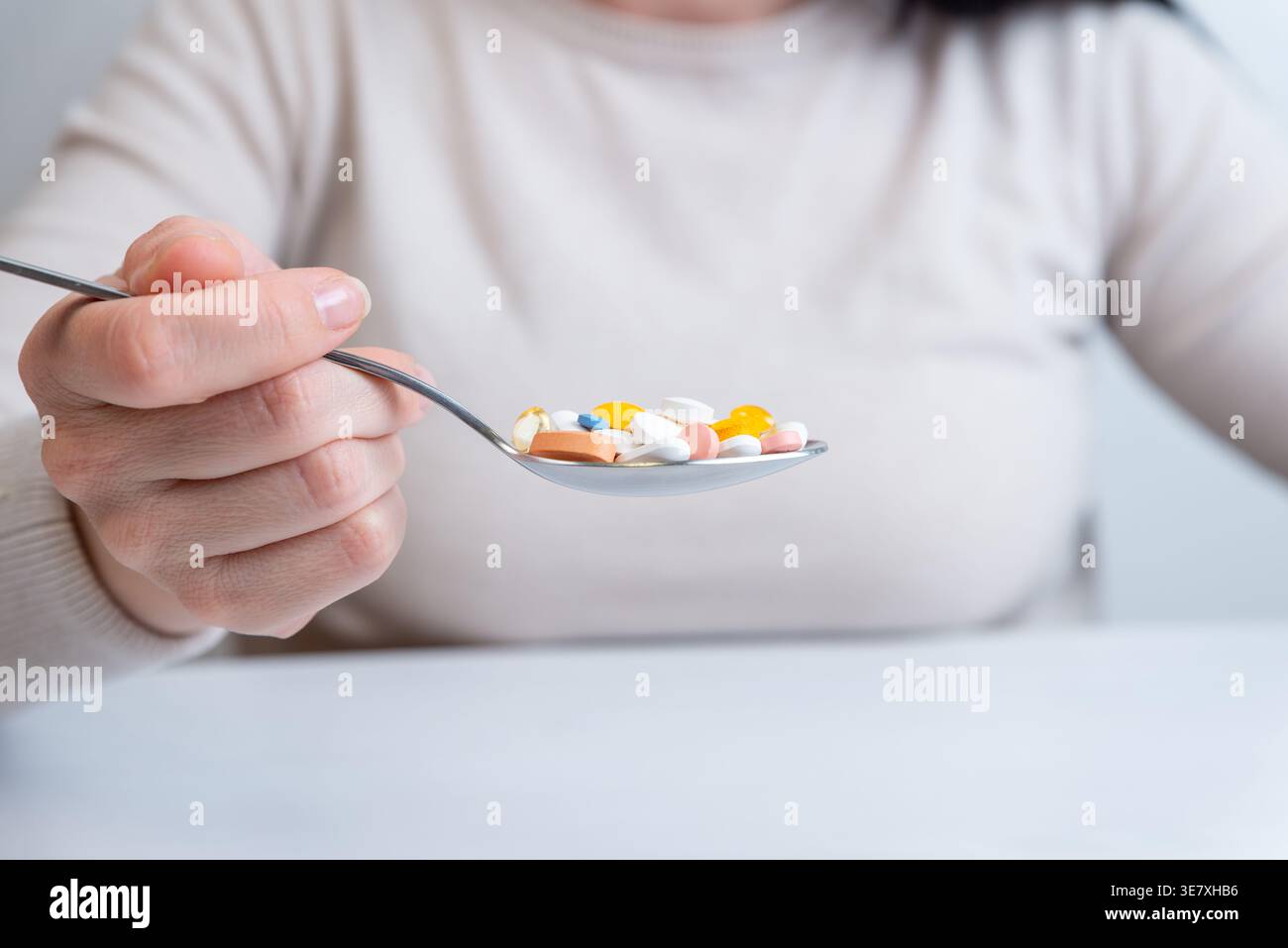 Persona che tiene il cucchiaio pieno di pillole, concetto di sovradosaggio e assunzione pericolosa di farmaci Foto Stock