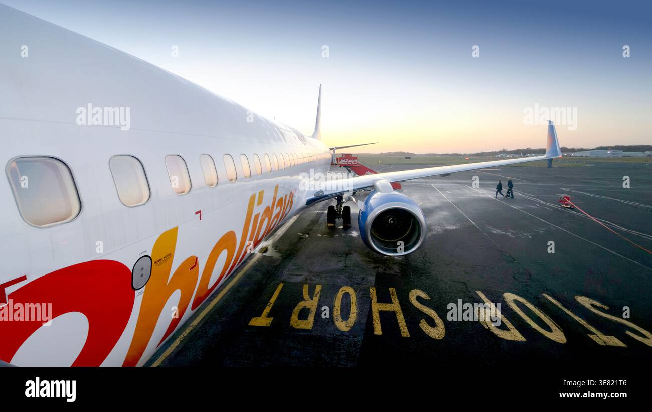 Aereo Jet2 parcheggiato sull'asfalto dell'aeroporto all'alba con motore e ala visibili Foto Stock