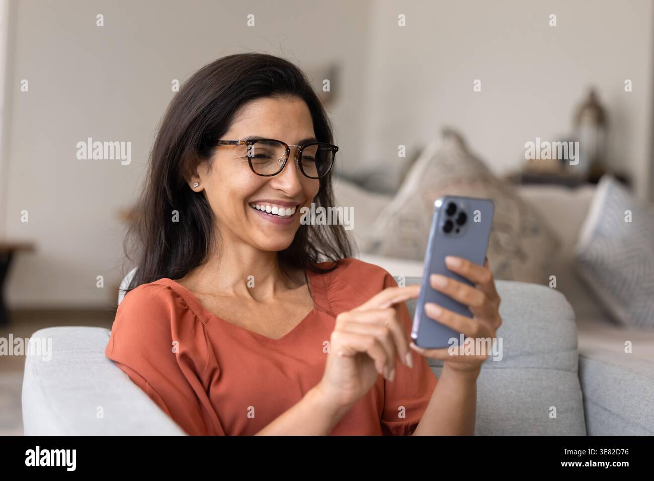 Donna sorridente che usa lo smartphone a casa Foto Stock