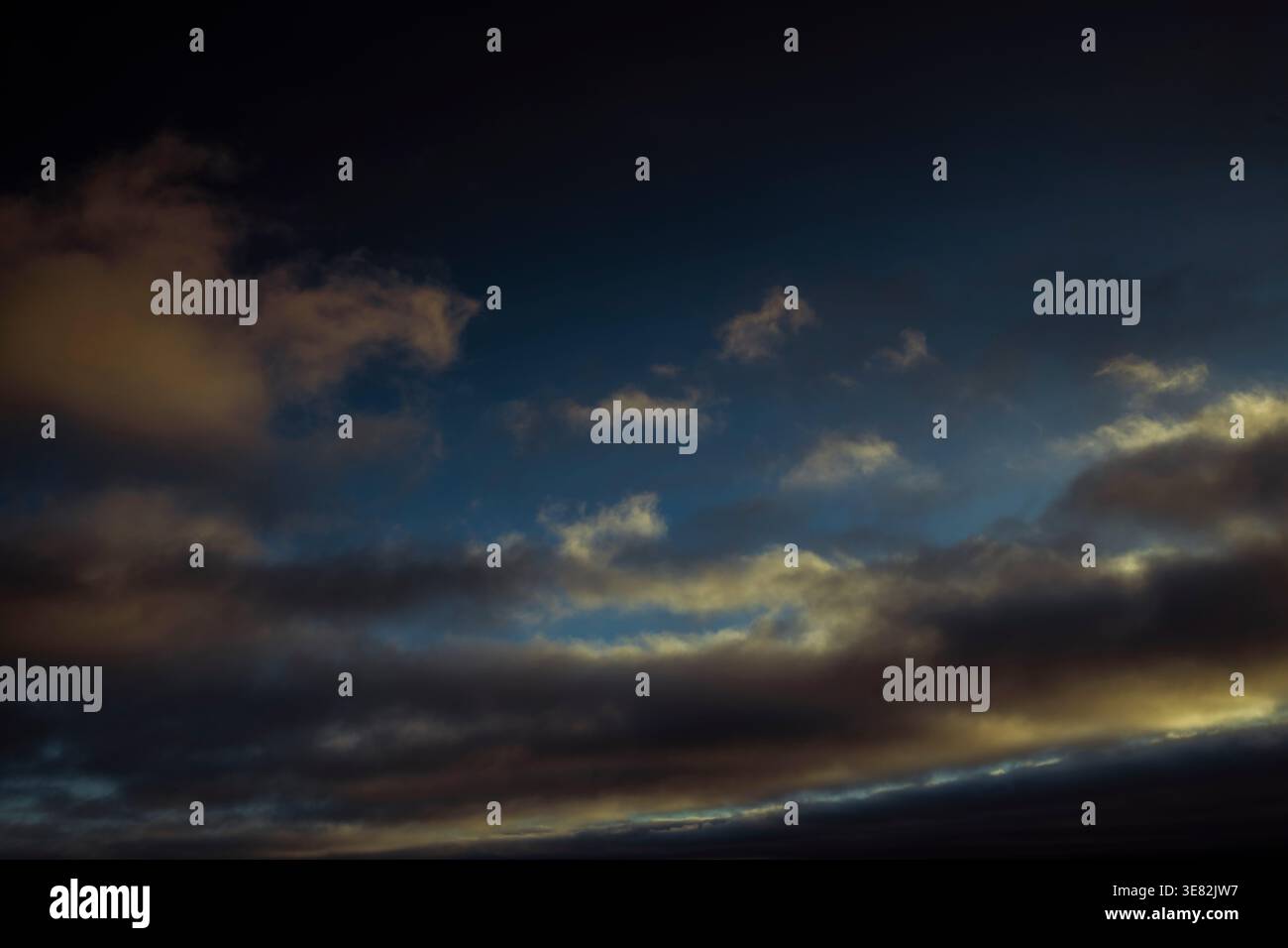 Il cielo è buio e nuvoloso, con poche nuvole sparse in tutto. Le nuvole sono basse e vicine al terreno, dando l'impressione di una giornata tempestosa Foto Stock