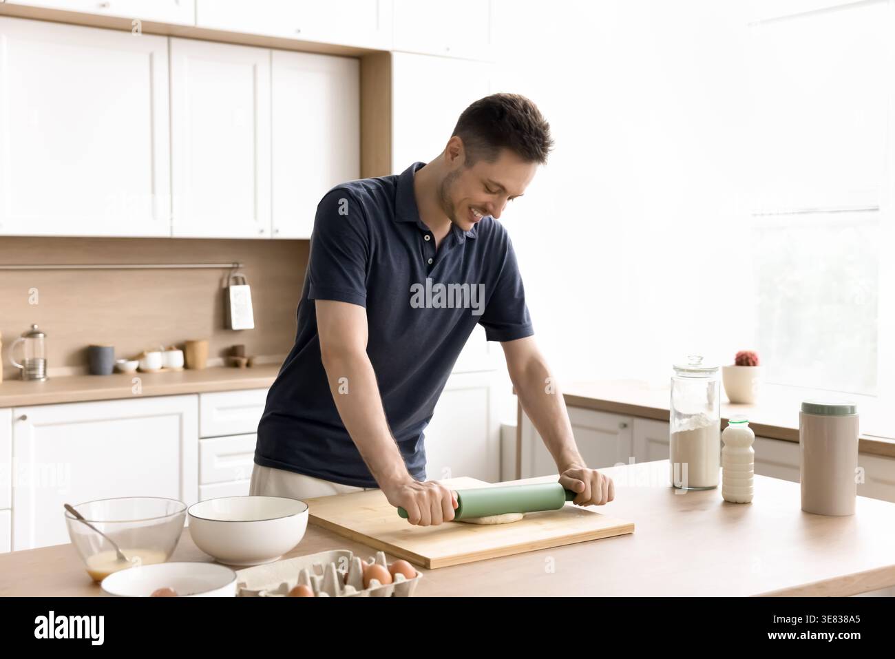 Uomo ispanico millenario che appiattisce l'impasto in una cucina moderna Foto Stock