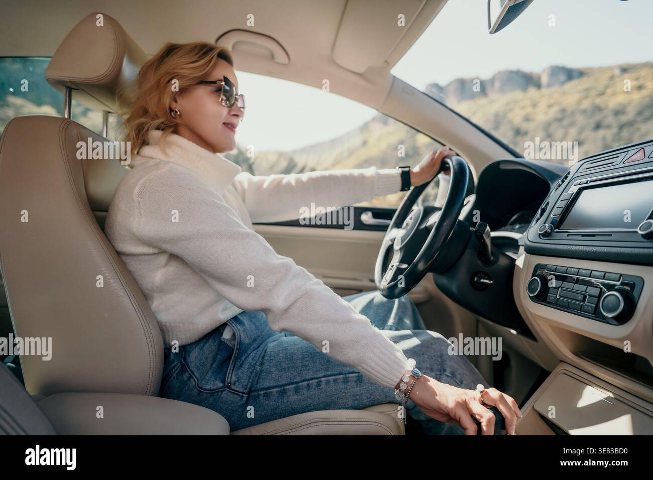 Giovane donna che guida un'auto in un giorno di sole Foto Stock