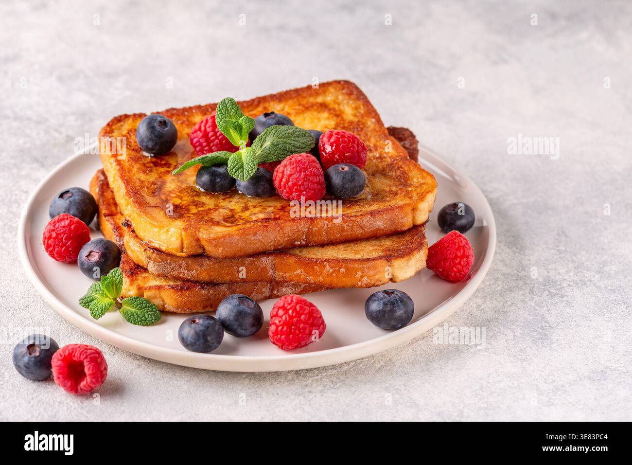 Toast alla francese con mirtilli, lamponi, sciroppo d'acero, colazione mattutina. Foto Stock