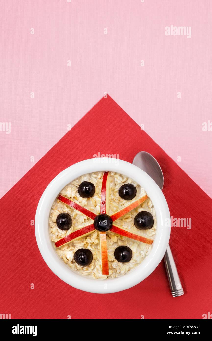 Ciotola bianca con avena, mele e uva notturna su sfondo rosso e rosa Foto Stock