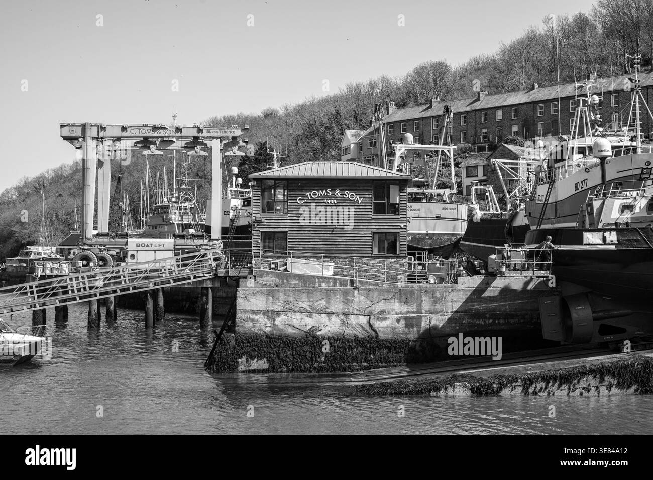 Vista in bianco e nero del porto di Polruan con molo in legno e barche ormeggiate, Cornovaglia, Regno Unito Foto Stock