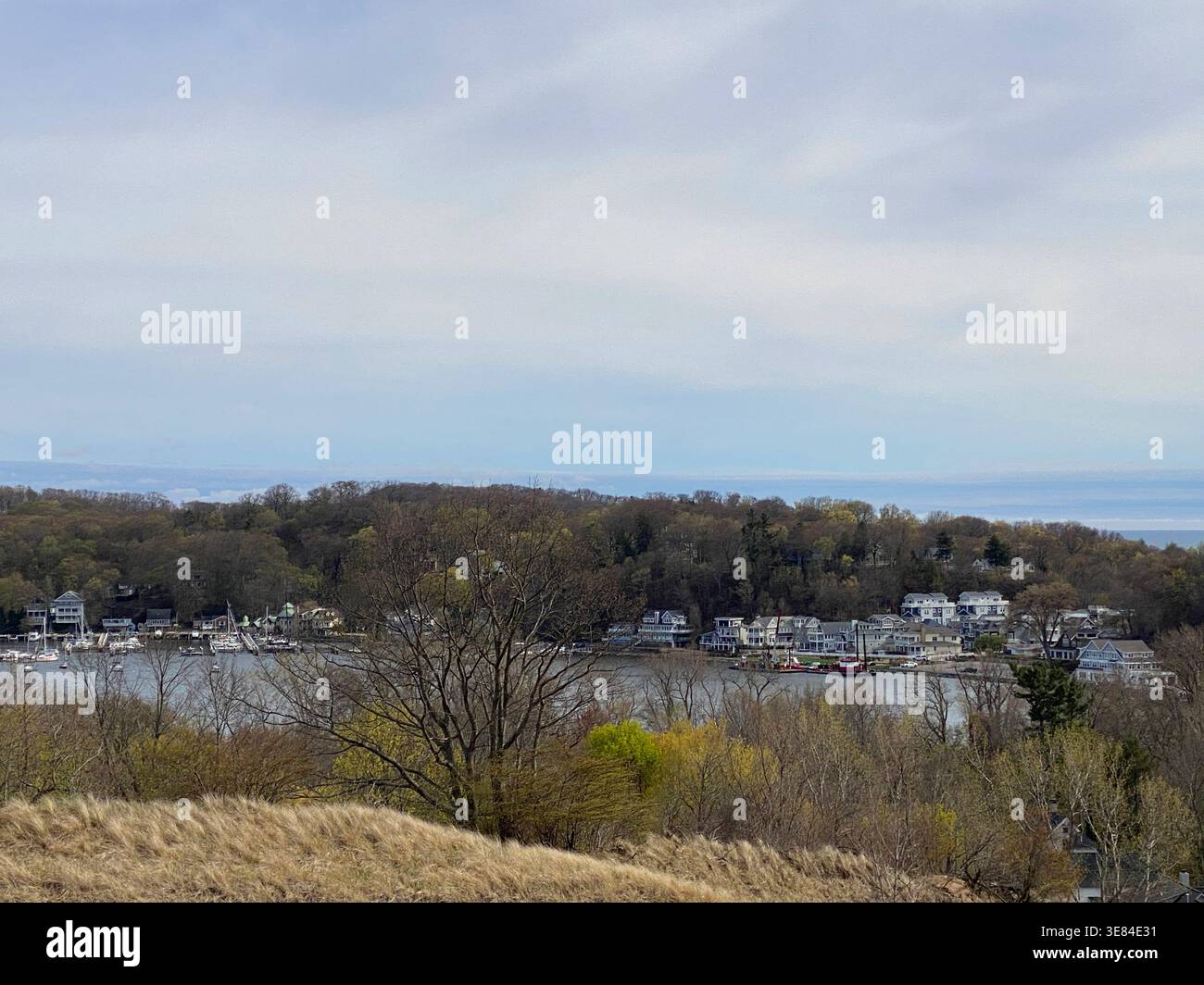 Guardando in basso dalla cima di una duna di sabbia alle case di lusso che costeggiano il lago Macatawa, circondato dalla foresta in Olanda, Michigan, Stati Uniti - Immagine stock catturata con smartphone