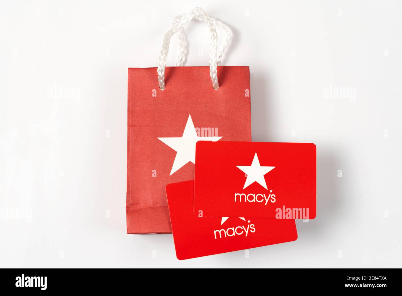 Novi, Michigan, Stati Uniti - 6 aprile 2026 : due buoni regalo Macys rossi con l'iconico logo della stella bianca posti davanti a una piccola borsa regalo di carta rossa abbinata con manici bianchi. Foto Stock