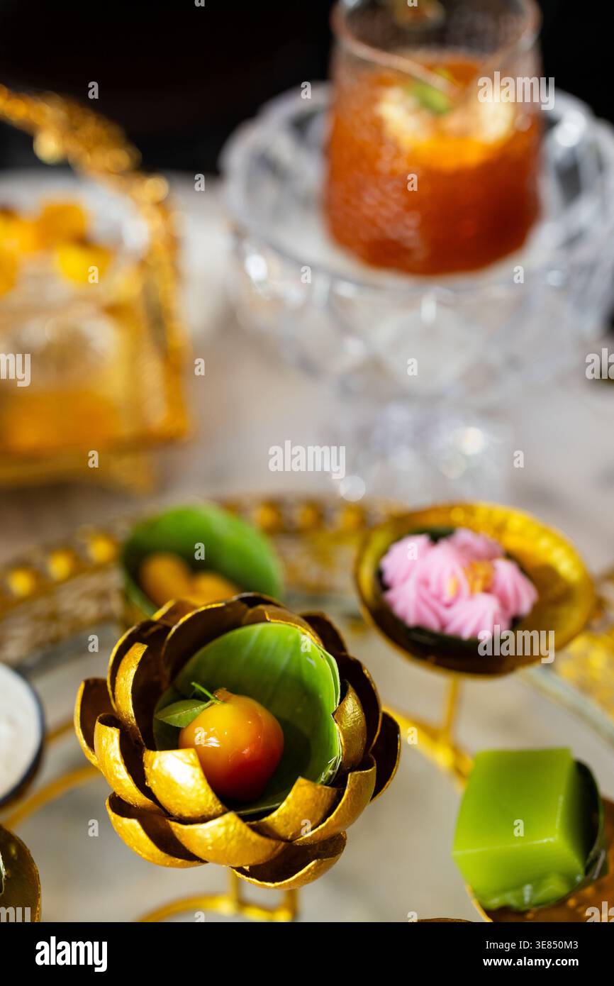 Tè pomeridiano di lusso su un tavolo in marmo con bancarelle dorate ornate che ospitano dessert assortiti e frutta, con tè freddo e bevande e bokeh Cafe bac Foto Stock