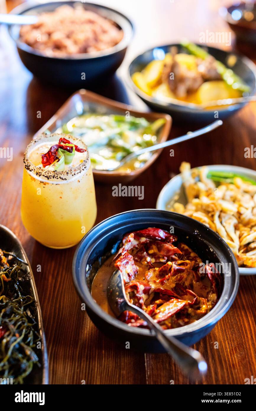 Piatto al peperoncino bhutanese, funghi, riso e cocktail agli agrumi con contorno al peperoncino, profondità di campo bassa, calda illuminazione del ristorante. Foto Stock