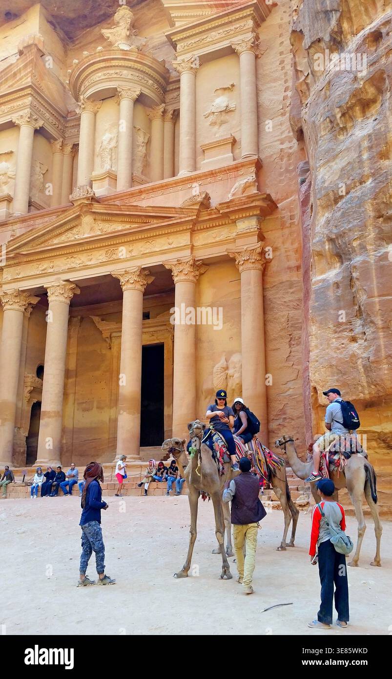 Petra, Giordania - 15 ottobre 2016: Le turisti donne sui cammelli posano per delle foto di fronte al famoso Tesoro al-Khazneh Foto Stock