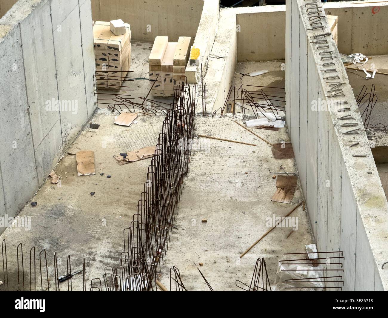 Fondamenta in calcestruzzo in costruzione con gabbia di armatura in acciaio esposta in una trincea, che forma pareti e soletta del pavimento. Il cantiere mostra casseforme, mattoni, Foto Stock