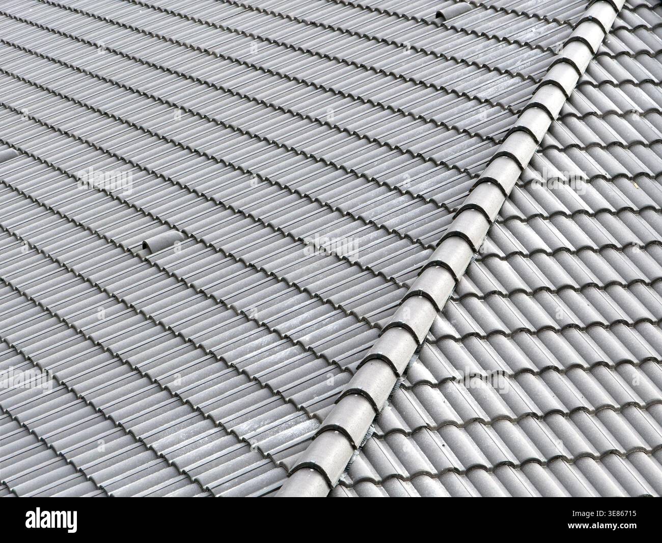 Vista ravvicinata di un tetto piastrellato in ceramica grigia con linea di copertura e ripetizione ondulata, per creare uno sfondo dalle texture architettoniche pulite per il const Foto Stock