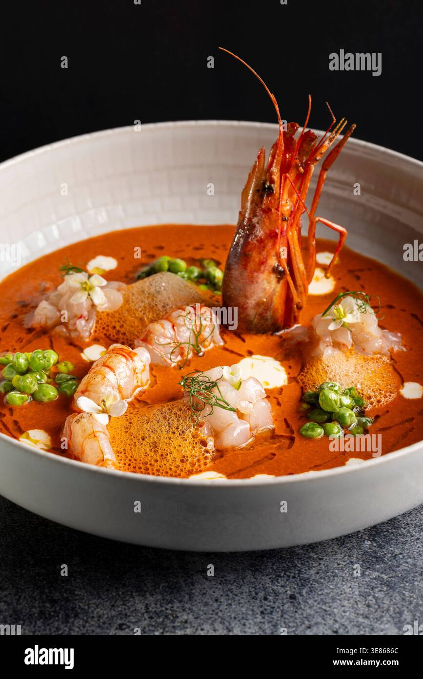 Elegante piatto da pranzo con tartare di gamberi e gamberi interi in salsa di gamberi setosi, con piselli, schiuma ariosa e salsa di agrumi brillante, sapientemente placcata Foto Stock