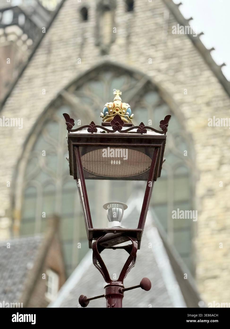 Un lampione stradale d'epoca coronato da dettagli eleganti si erge graziosamente davanti a una grande vecchia chiesa, mescolando fascino storico con un'atmosfera romantica - Immagine stock catturata con smartphone