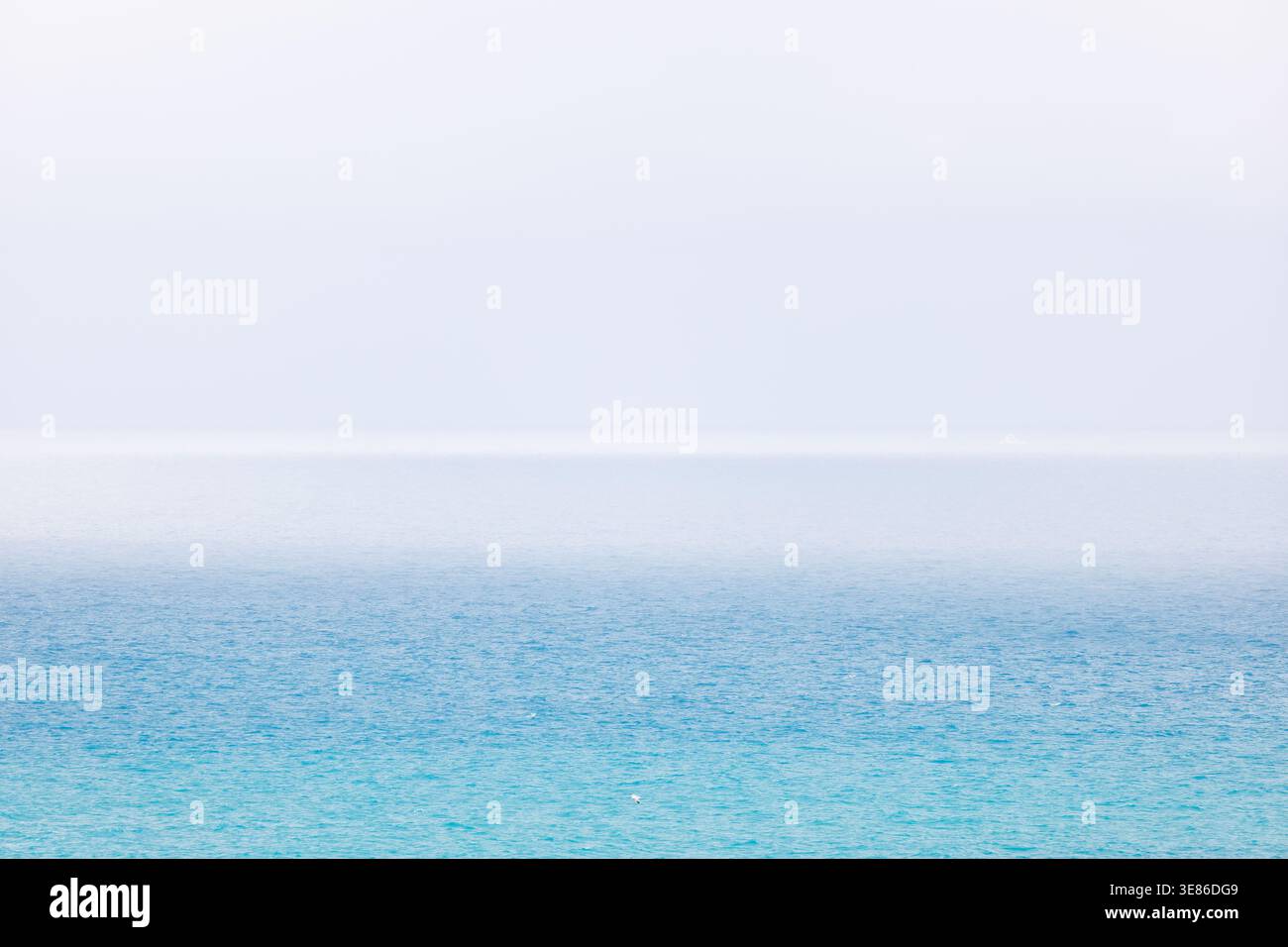 Un'ampia e alta vista del blu Mar Mediterraneo vicino a Villajoyosa. L'acqua ha un gradiente morbido che si fonde in una fitta foschia bianca. Nel centro Foto Stock
