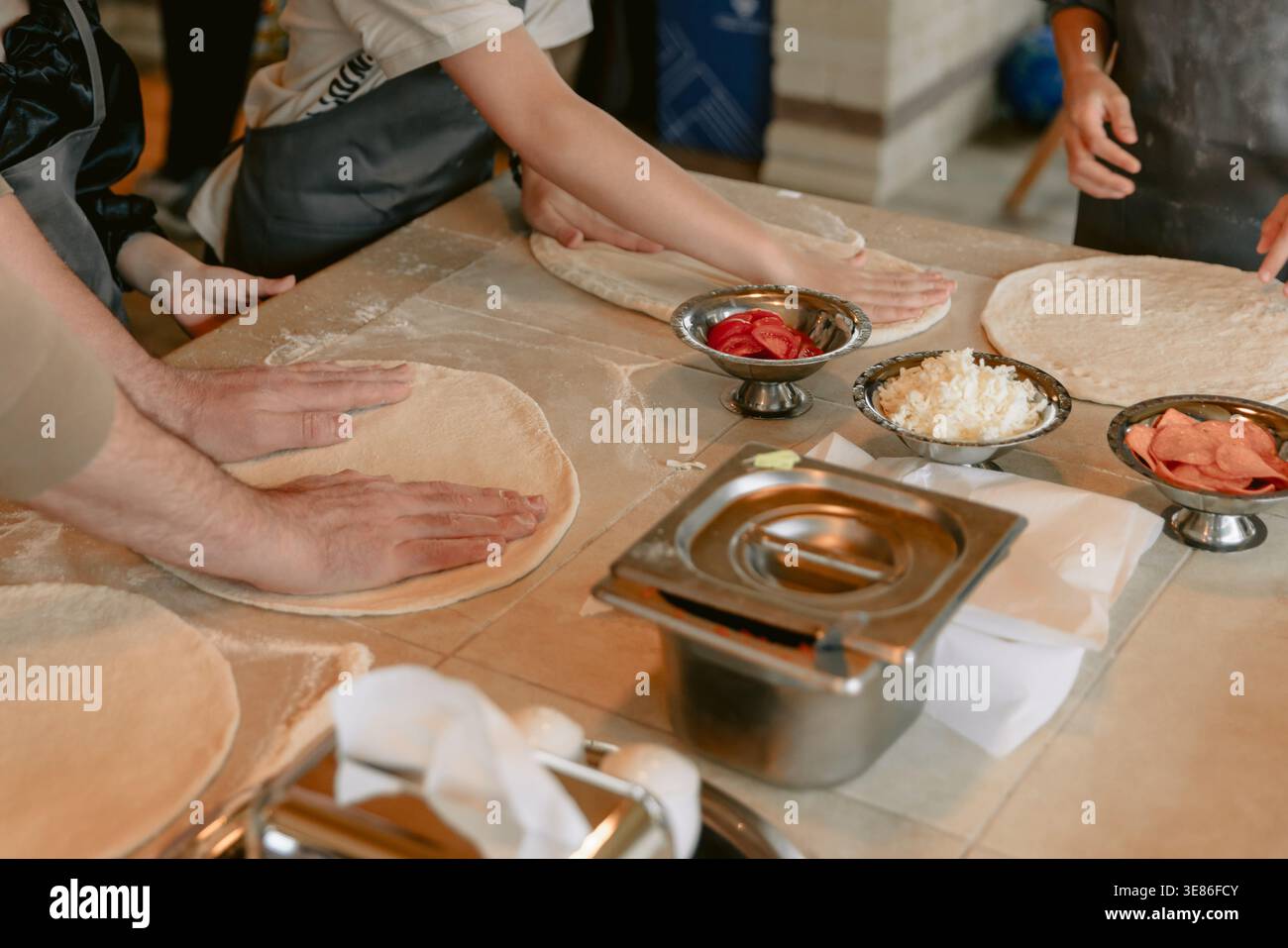 Mani che preparano l'impasto per pizza con ingredienti freschi in cucina o al ristorante Foto Stock