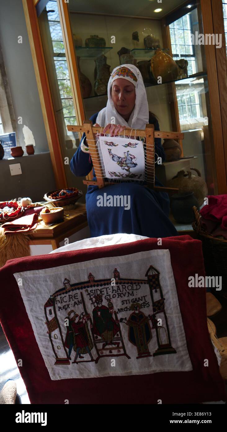 Un memeber della società di rinnovamento vichinga mostra arazzi medievali al Winchester City Museum Foto Stock