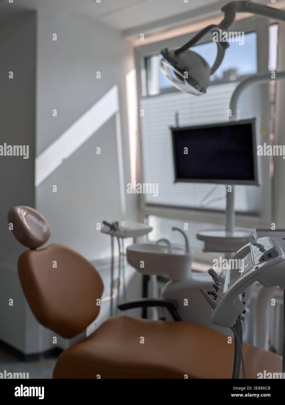 Sedia dentale e lampada a soffitto nella clinica odontoiatrica illuminata dalla luce del giorno Foto Stock