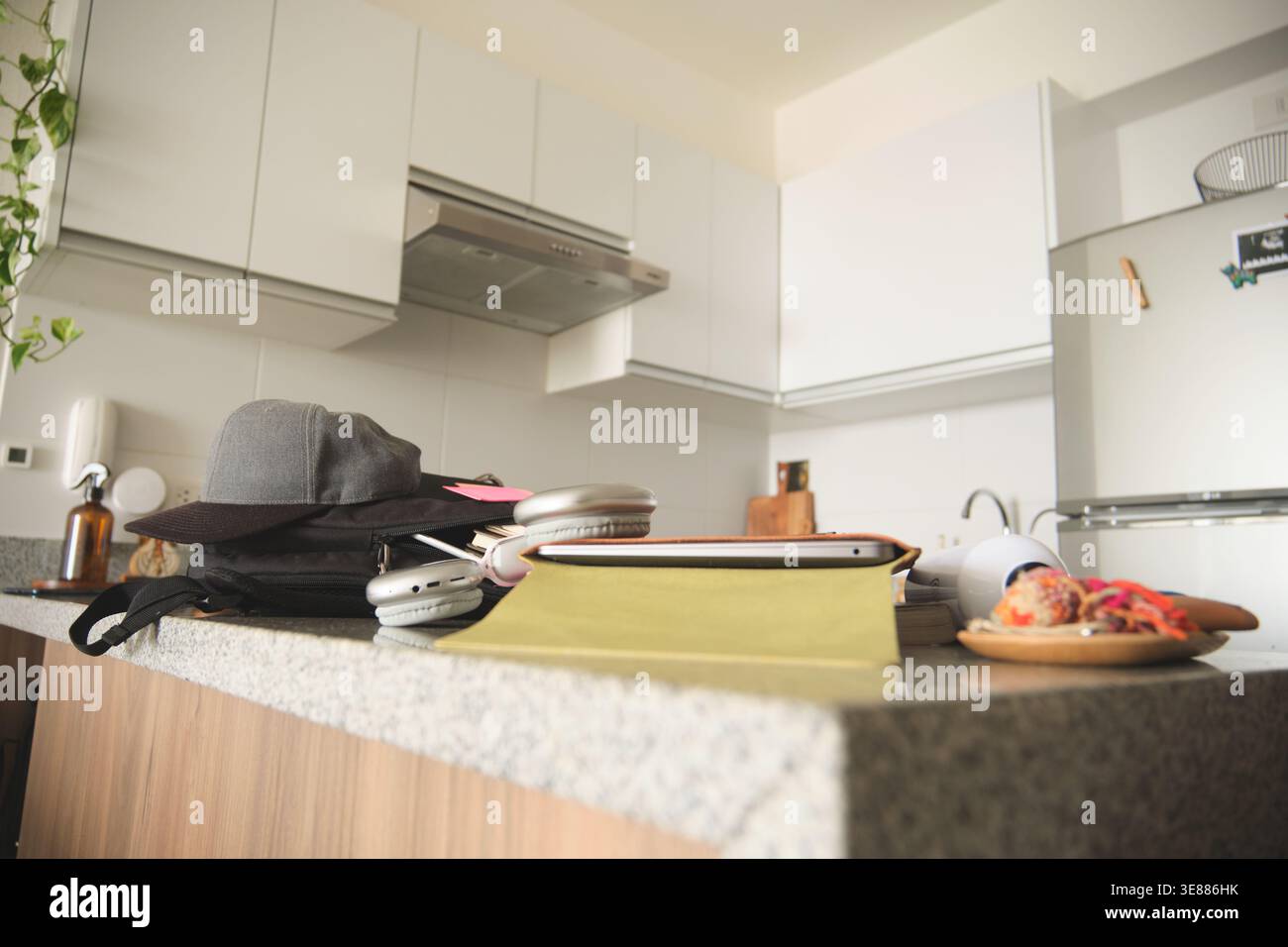 Gli oggetti quotidiani degli studenti riempiono un bancone della cucina come spazio di lavoro temporaneo Foto Stock