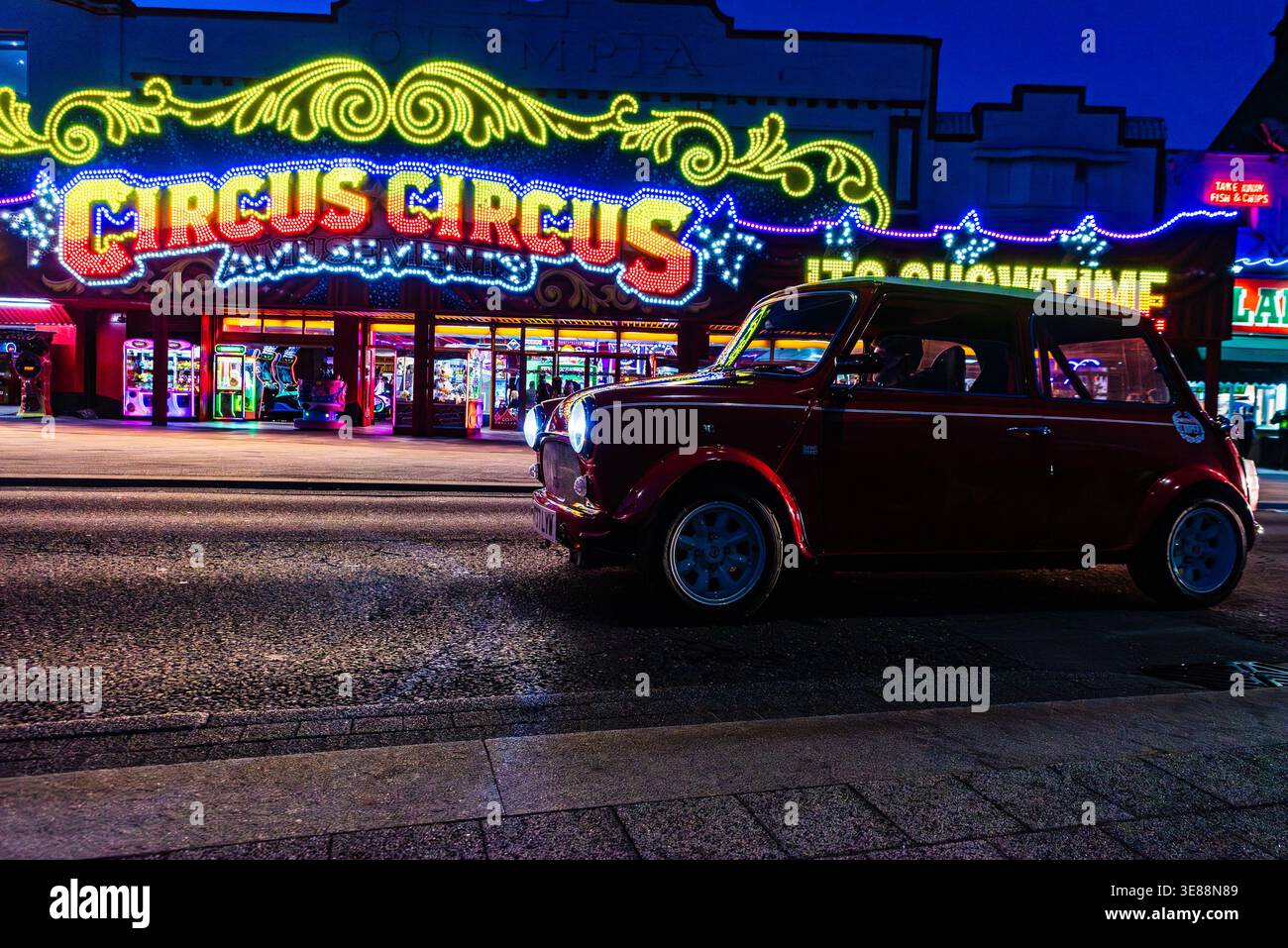 Crociera in mini-car classica a Southend on Sea, Essex, Regno Unito, un luogo popolare per raduni personalizzati e classici di veicoli, passando davanti a divertimenti illuminati Foto Stock