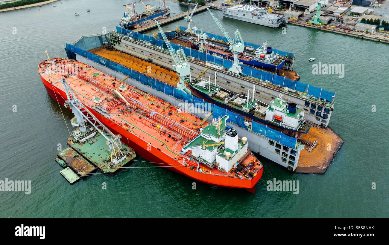 Vista dall'alto di una grande petroliera in un bacino di carenaggio con gru da cantiere e infrastrutture marittime durante la manutenzione delle navi. Foto Stock