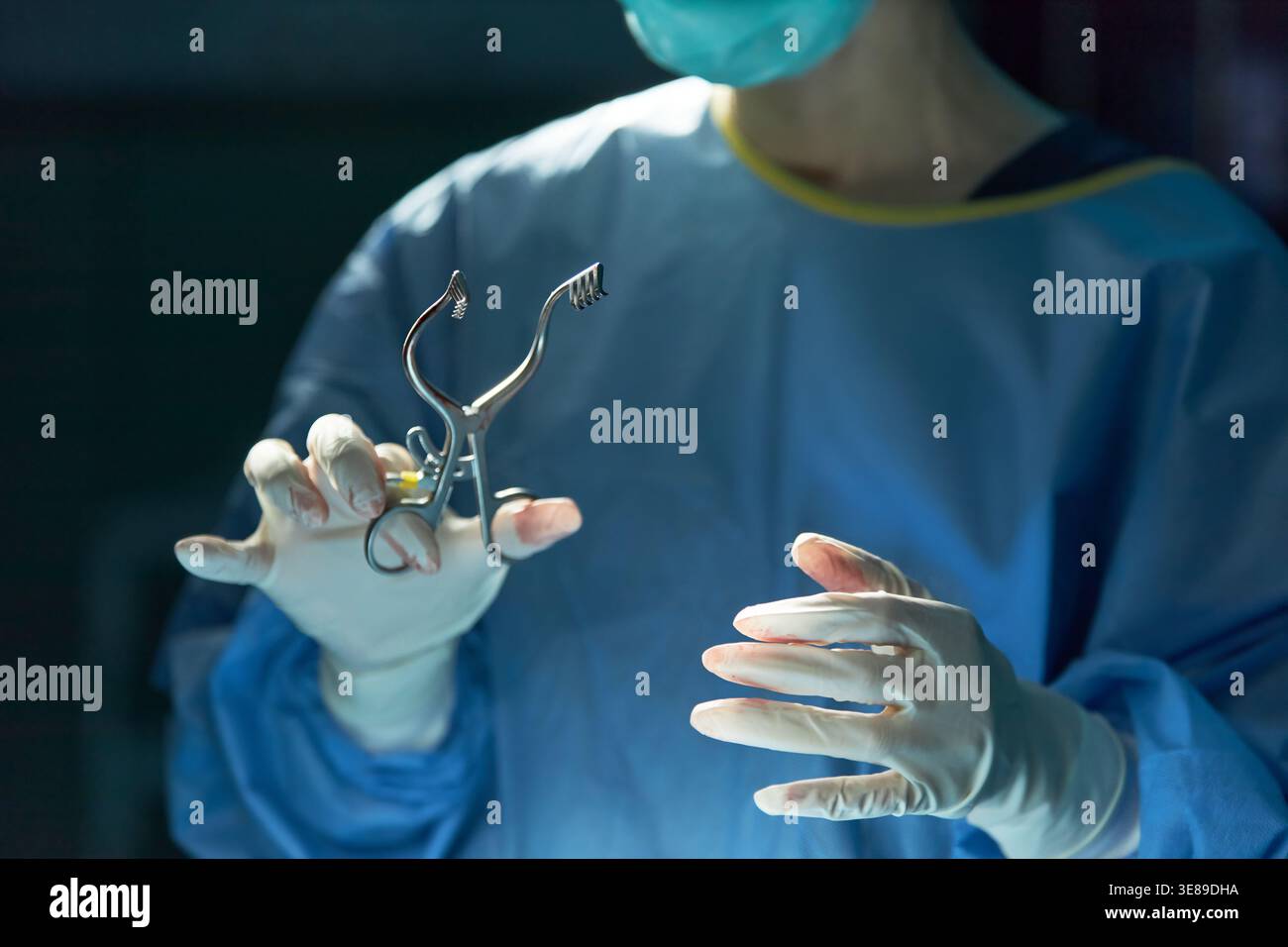 Primo piano del chirurgo che tiene in mano il divaricatore chirurgico durante l'operazione, mostrando procedure mediche sterili e precisione. Utile per marketing sanitario, servizi ospedalieri, formazione chirurgica Foto Stock