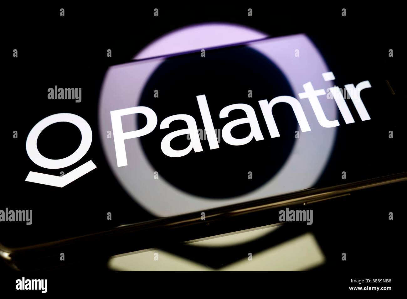 Parigi, Francia - 10 aprile 2026: Il logo Palantir sullo schermo di uno smartphone, posizionato su una superficie riflettente con una proiezione luminosa circolare. Foto Stock