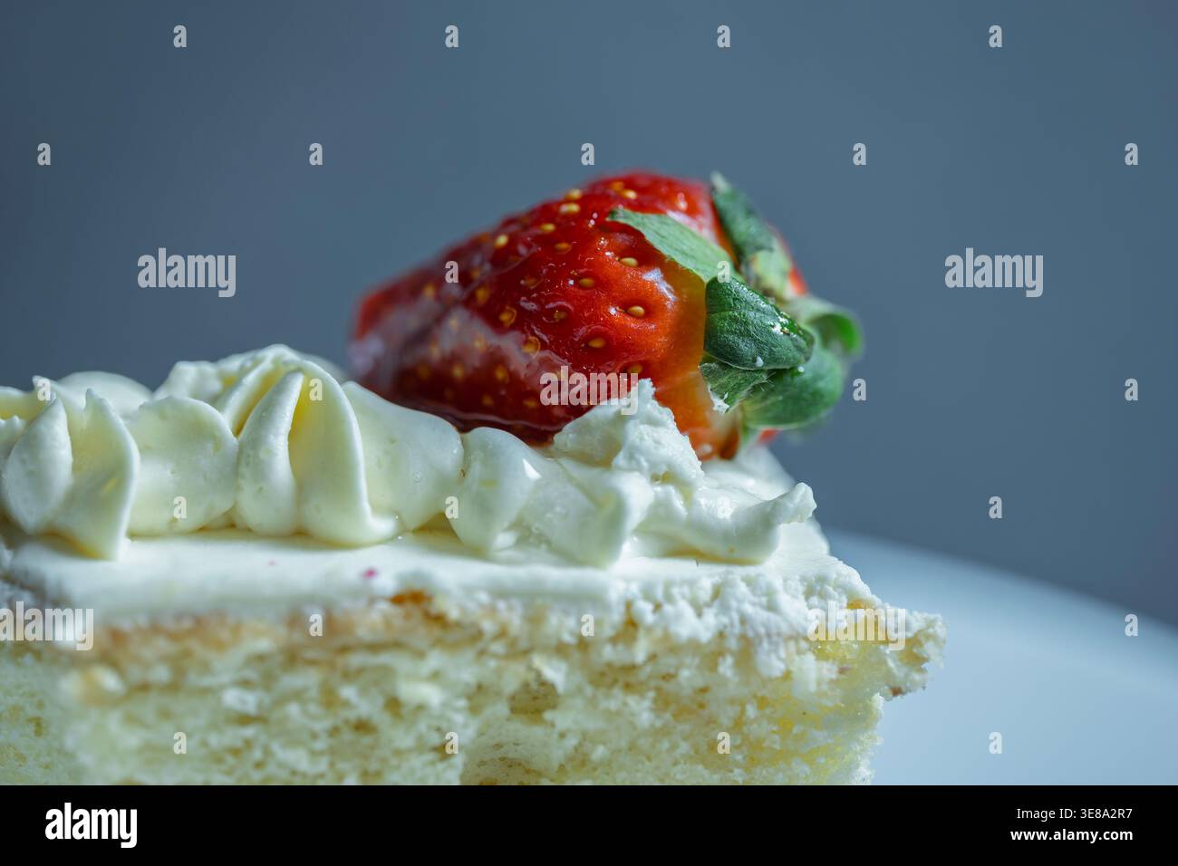 Primo piano di una torta di spugne umida con panna montata e una fragola rossa matura Foto Stock