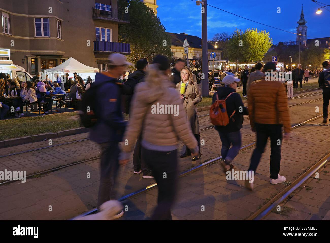 Il giornalista sta riportando per le strade di Budapest, Ungheria, la notte delle elezioni parlamentari del 2026 tra la folla celebrante Foto Stock