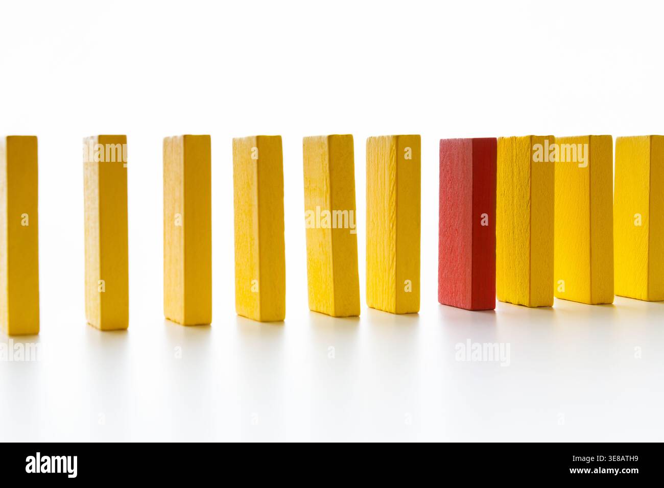 Collezione di domini in giallo e un pezzo rosso disposti in linea retta su una superficie piana Foto Stock