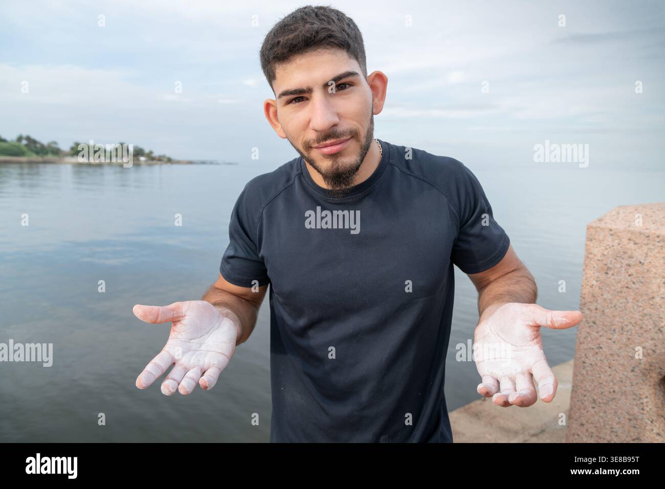 Uomo con polvere di gesso sulle mani che si prepara per una routine di fitness all'aperto vicino all'acqua Foto Stock