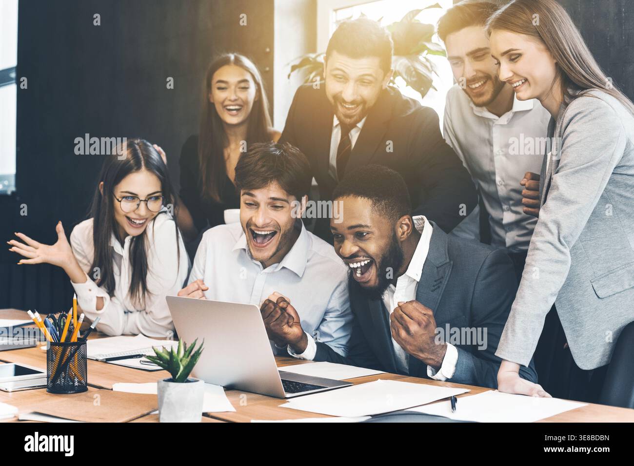 Uomini d'affari felici che celebrano il successo guardando un notebook Foto Stock