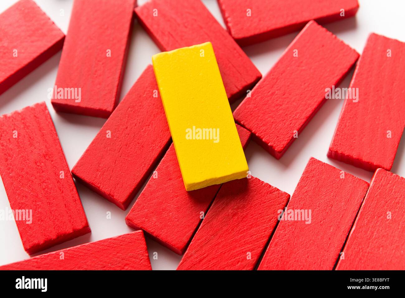 Un blocco di legno giallo su un gruppo di quelli rossi Foto Stock