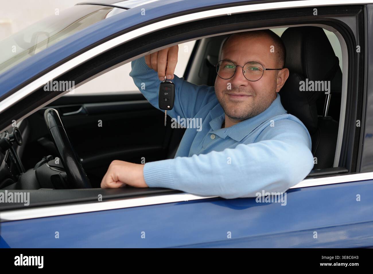 Uomo sorridente seduto in macchina tenendo le chiavi dell'auto ritratto dell'autista Foto Stock