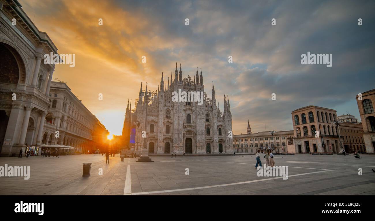 Piazza Duomo di Milano è quasi vuota all'alba, illuminata da una luce calda che filtra tra gli edifici. Foto Stock