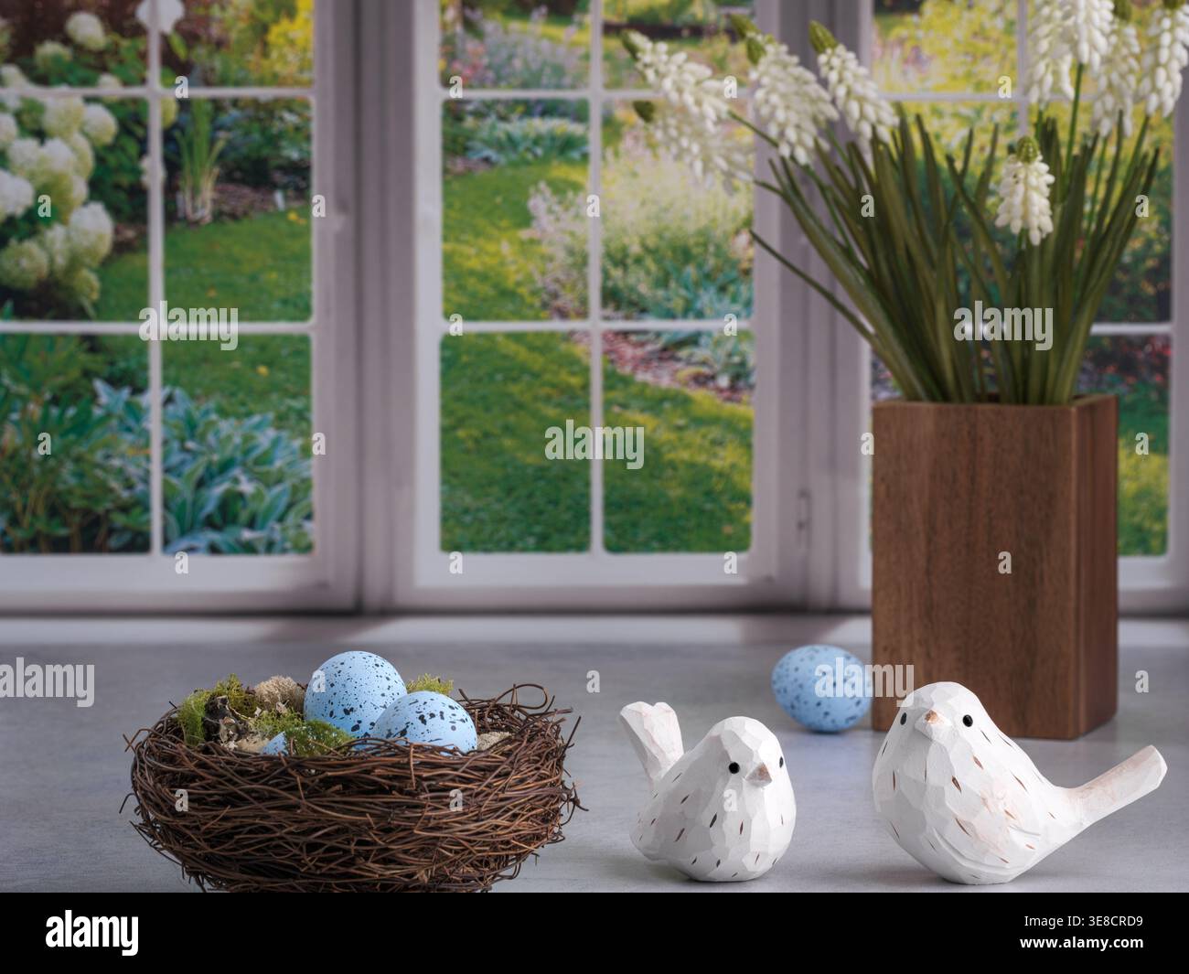 Cucina luminosa con finestre colorate e tranquille del giardino naturale e nido primaverile di robin con uova macchiate blu. Uccelli bianchi in legno intagliato. Legno marrone Foto Stock