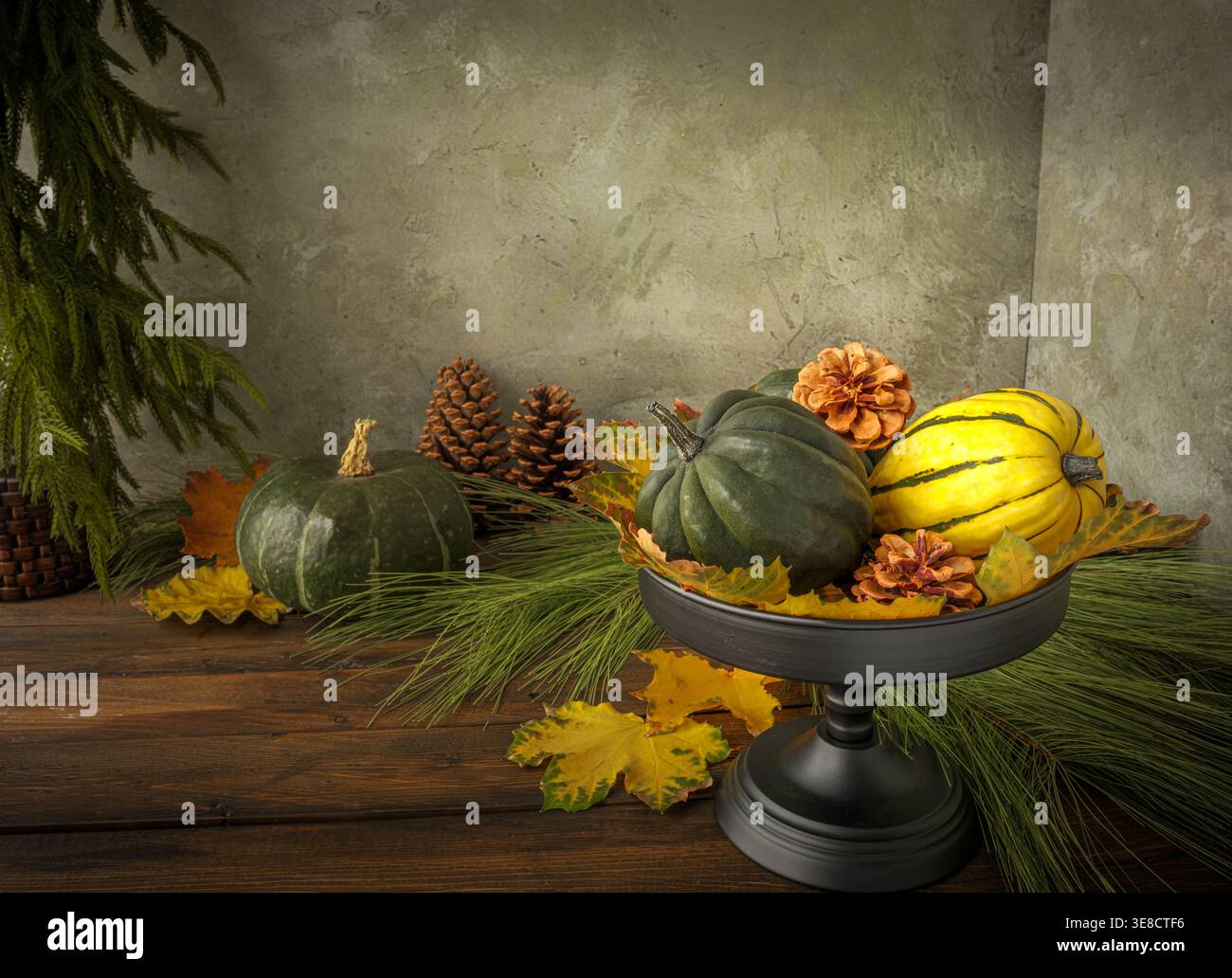 Vassoio a più piani con zucca e buongustai con foglie d'oro e pinne su fondo in gesso rustico e tavolo in legno. Aghi di pino Norfolk. Autunno Foto Stock