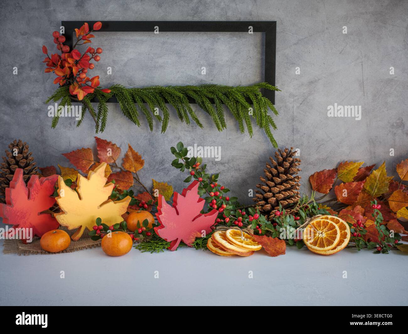 Decorazioni con foglie autunnali in legno, cornice nera appesa, rami di pino del Norfolk, arance, vegetazione come decorazione natalizia per le festività autunnali sfondo neutro Foto Stock
