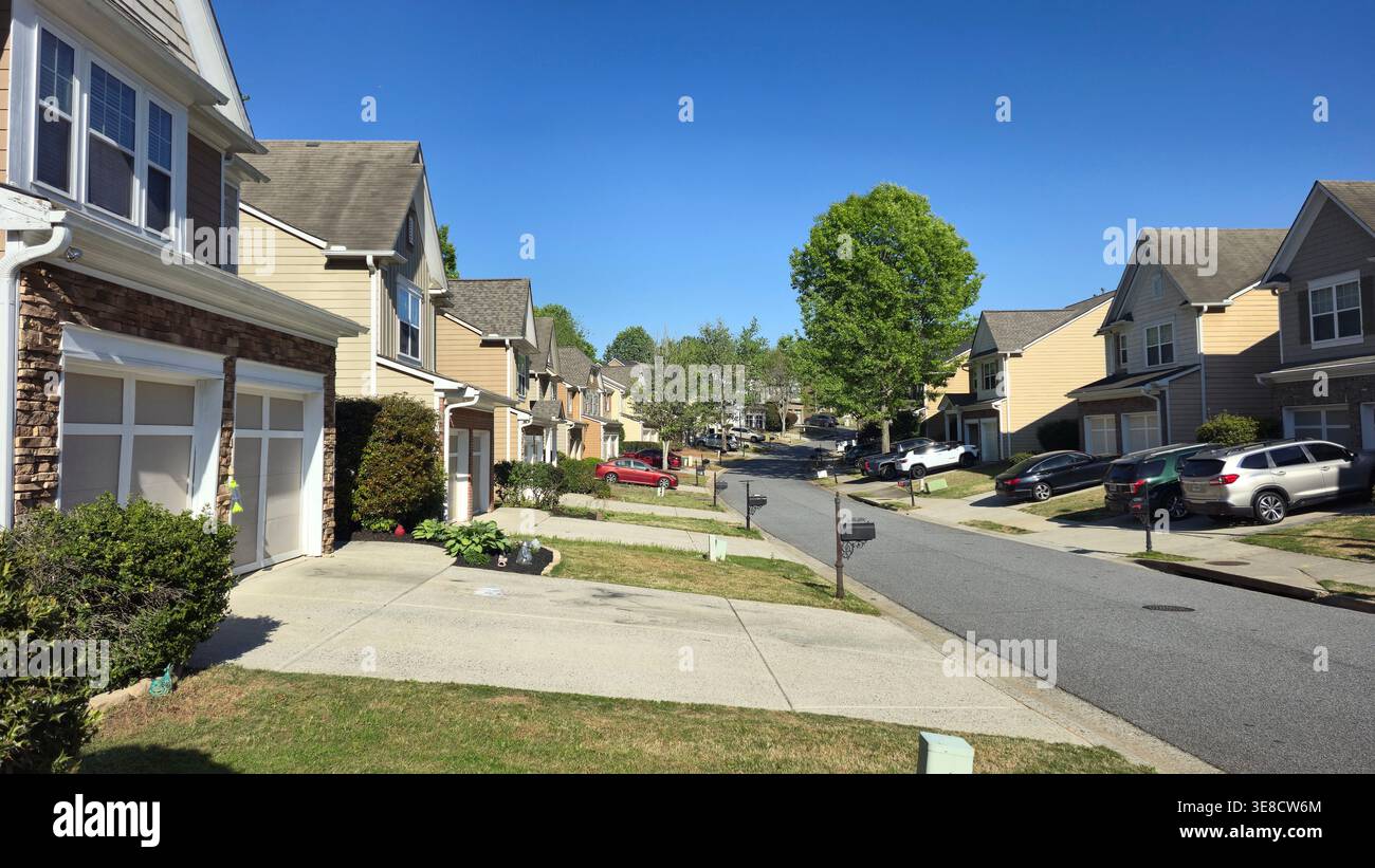 Strada residenziale suburbana con moderne case familiari, vialetti e auto parcheggiate nelle giornate di sole nel quartiere americano Foto Stock