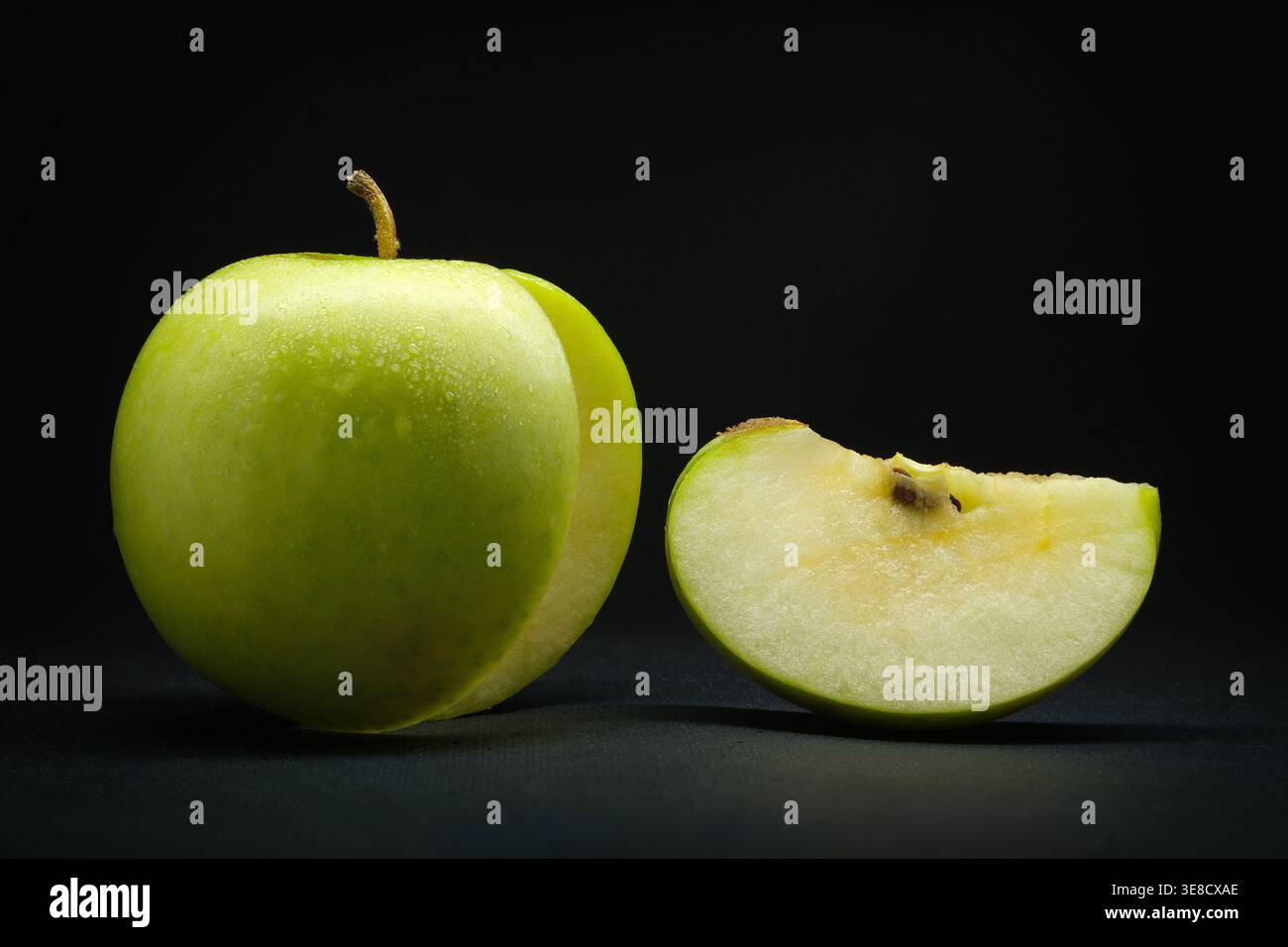Mela verde fresca con fette su sfondo nero, primo piano succoso e salutare frutta Foto Stock