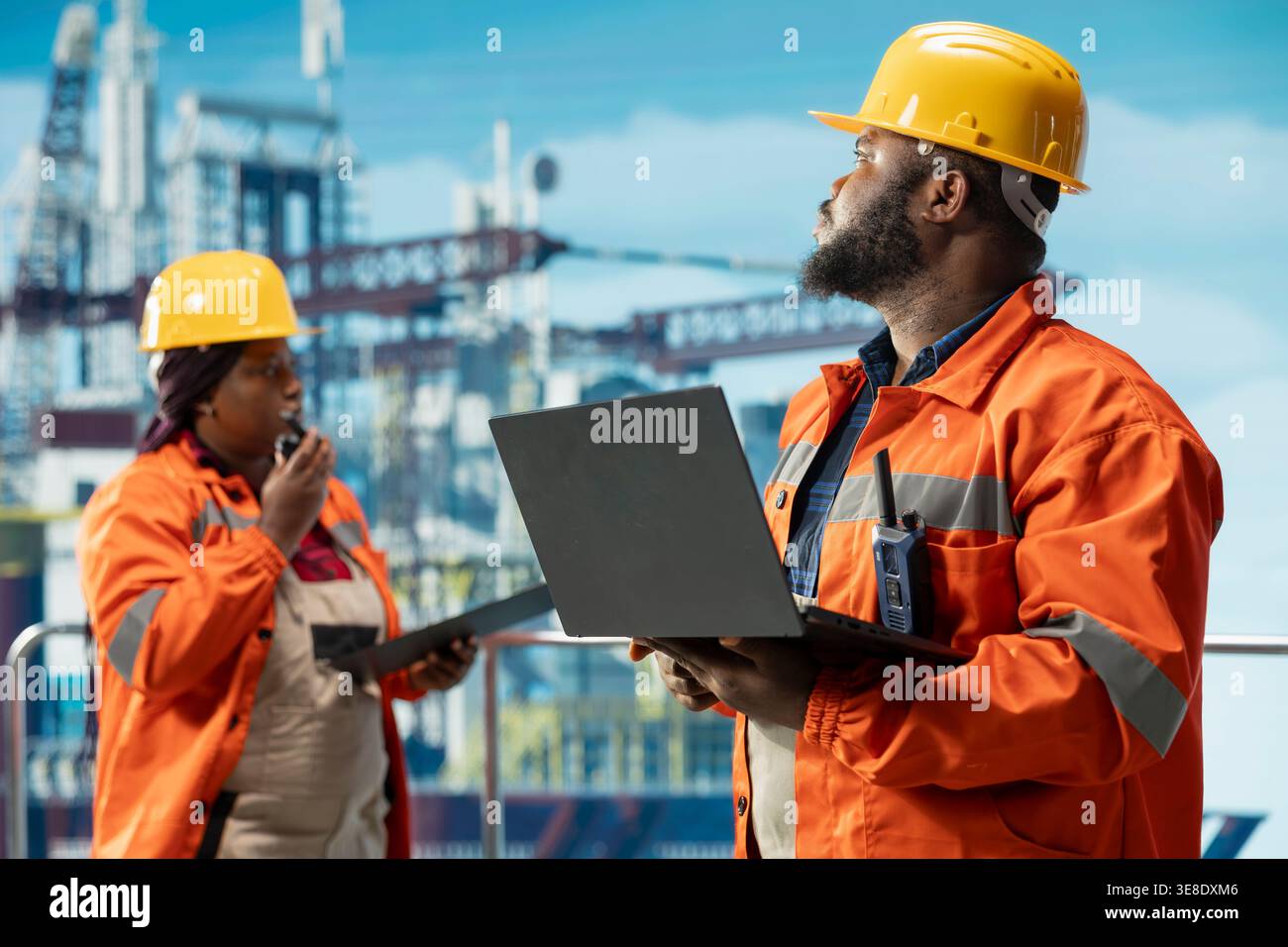 Team di tecnici di perforazione offshore che monitorano le operazioni utilizzando laptop e tablet sul ponte della piattaforma petrolifera. I colleghi del carro di perforazione per il lavoro di squadra che esaminano le operazioni energetiche utilizzando i dispositivi Foto Stock