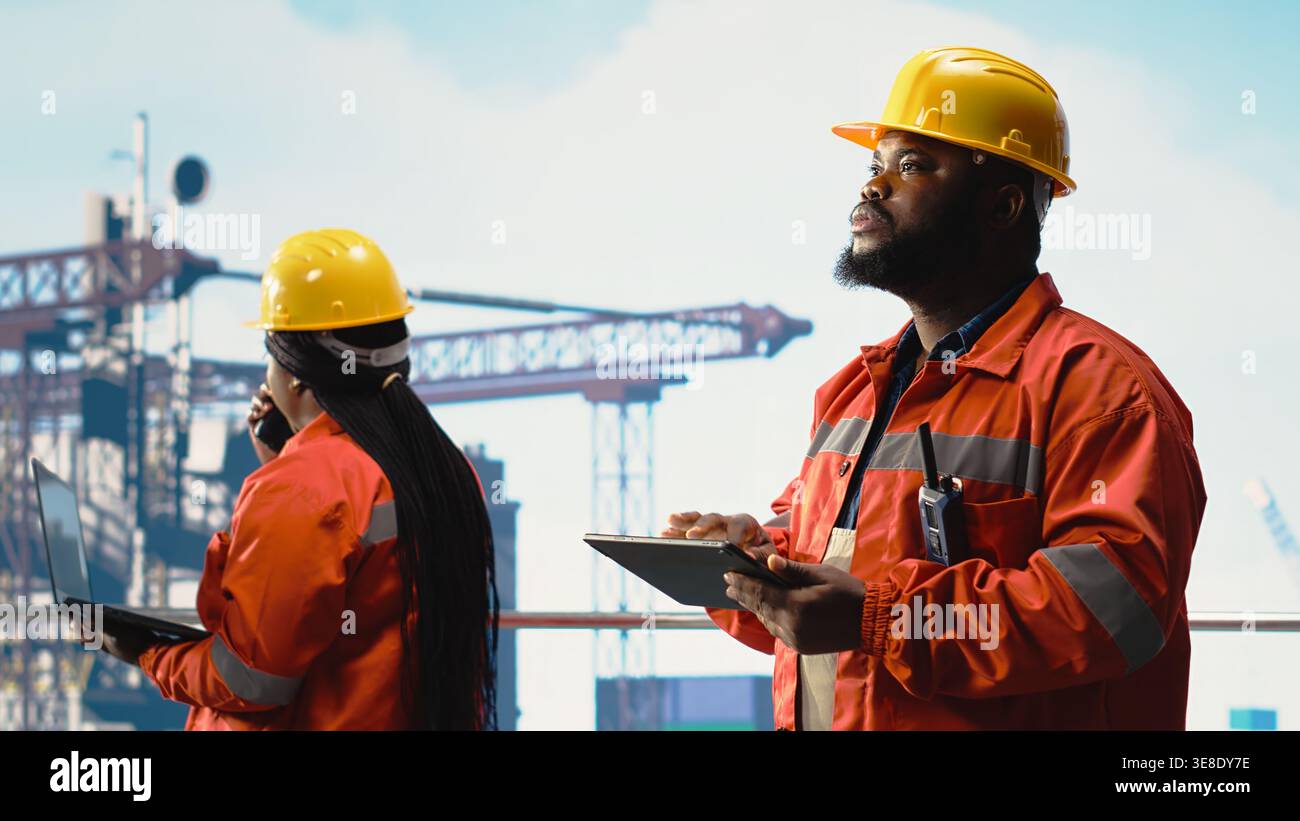 Gli ingegneri dell'equipaggio della piattaforma offshore supervisionano le operazioni del ponte con i dispositivi, garantendo la conformità ai protocolli di sicurezza. I lavoratori delle piattaforme petrolifere che effettuano controlli sulle attrezzature delle piattaforme di perforazione Foto Stock