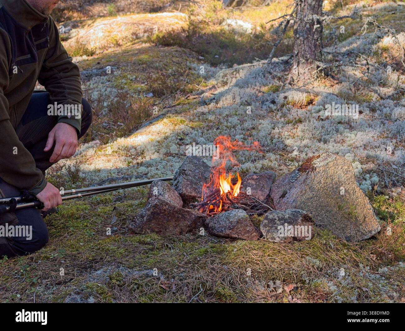 Uomo che usa firestarter per accendere il fuoco di campo nella foresta Foto Stock