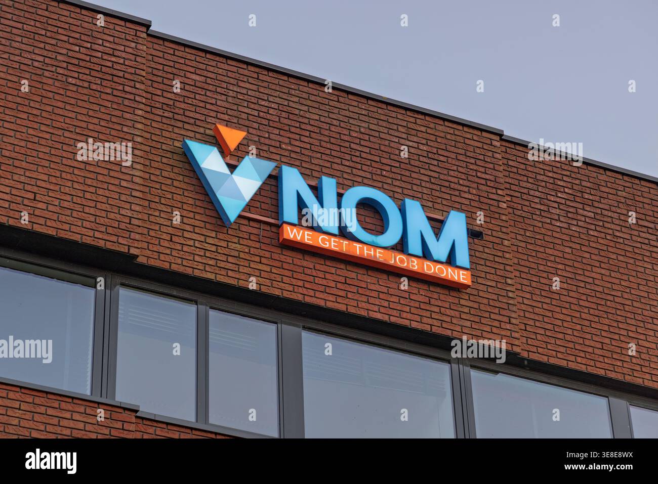 Utrecht, Paesi Bassi, 1° aprile 2026. Vista esterna del logo del marchio NOM e dello slogan "We Get the Job Done" montati su una moderna facciata in mattoni rossi. Foto Stock