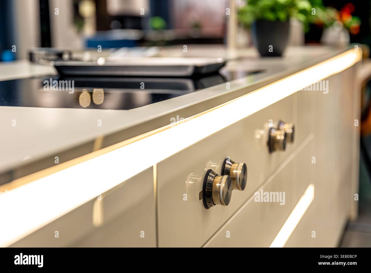 Cucina di lusso dal design isolano. Piano cottura e illuminazione a strisce LED integrata. Foto Stock